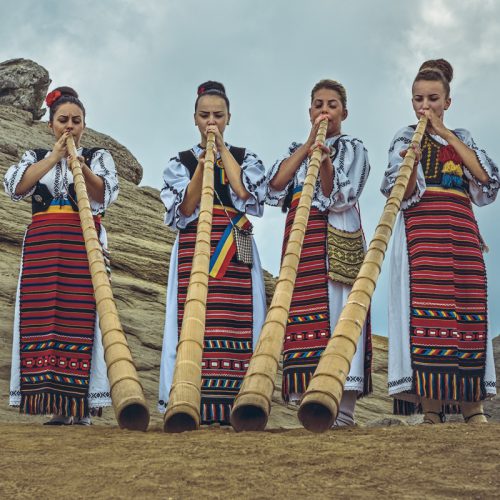 Bucegi Mountains, Romania - August 6, 2016: Group of Romanian female tulnic players dressed in colorful traditional costumes on Bucegi mountains plateau near the legendary Sphinx megalith.